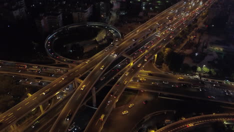 aerial shot of a multi layer express road junction at night with heavy traffic