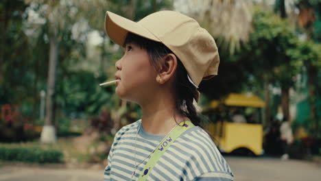 young girl enjoying a lollipop in a park