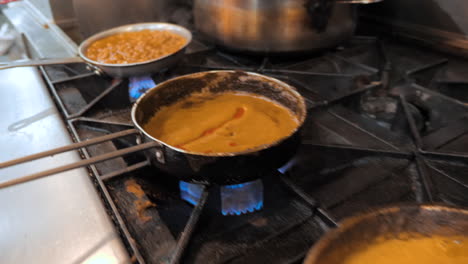 Indian-dishes-simmer-on-stove,-sauces-cook-in-restaurant-kitchen,-steady-slider----HD