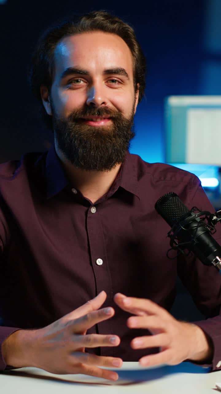 Video verticale verticale di un creatore di contenuti ottimista che conduce uno spettacolo online in uno studio con luci RGB