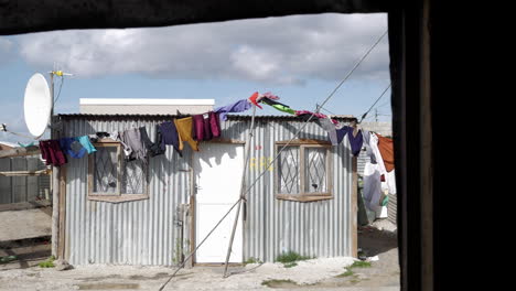 washing flapping in front of shack in township, shot from within opposite shack