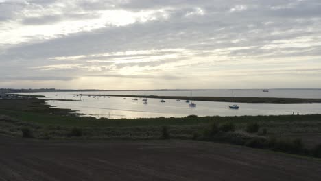 atardecer sobre barcos amarrados con reflejos en el agua y nubes grises