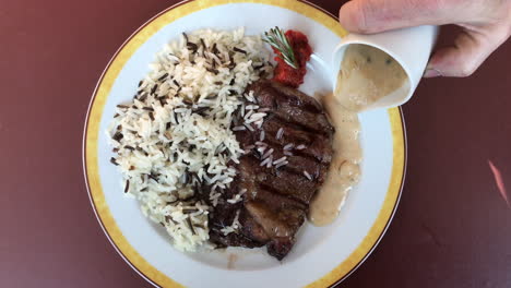 Hinzufügen-Von-Pfeffersauce-Zu-Steak-Und-Reis-High-Angle-View