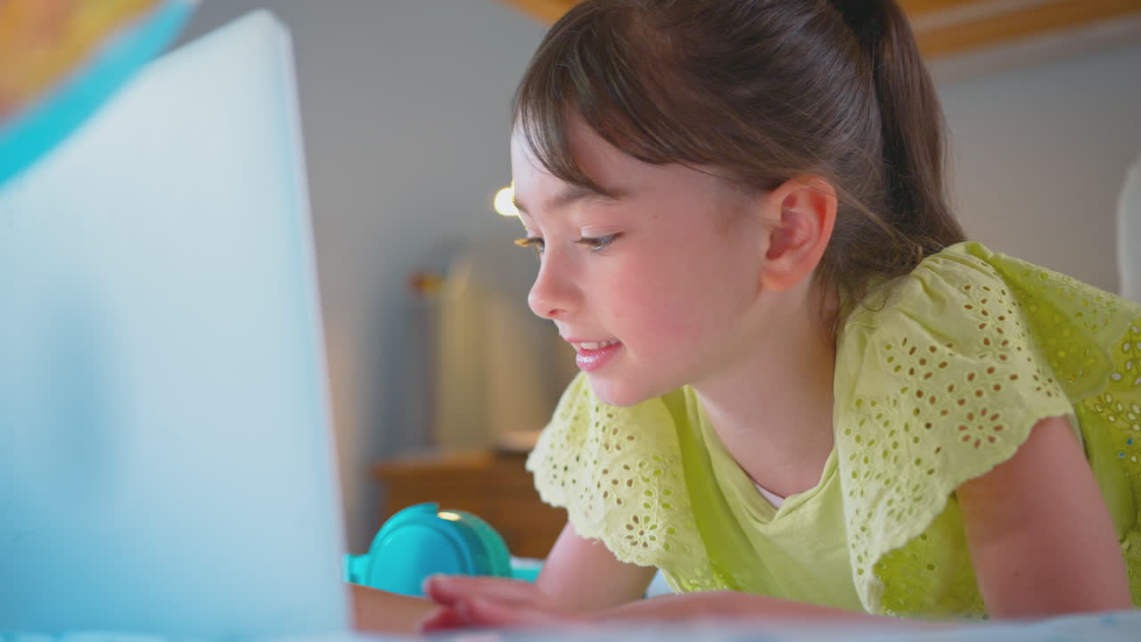 chica en el dormitorio acostada en la cama usando la computadora portátil para hacer la tarea