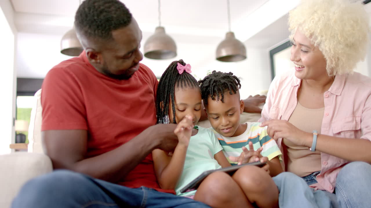 Famiglia afroamericana seduta insieme, che guarda un tablet