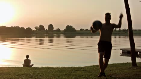 hombre haciendo malabares con una pelota de fútbol cerca de un lago