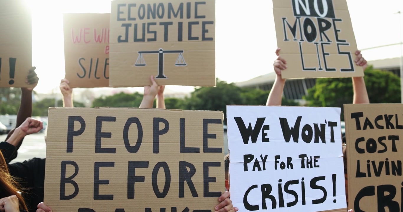 Manifestanti che reggono cartelli per chiedere giustizia economica e sociale