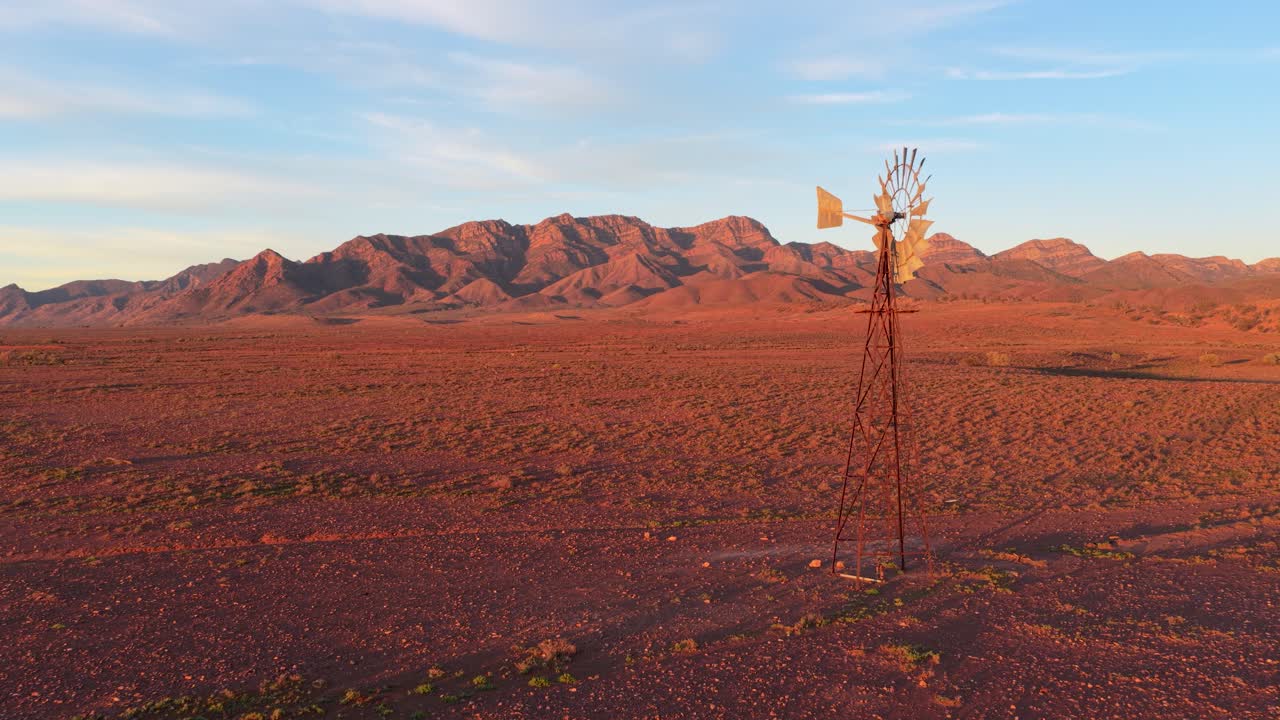 Drone pulls back to show windmill and vibrant red landscape in Flinders Ranges, South Australia
