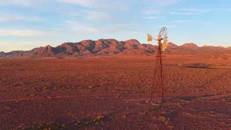 drone pulls back to show windmill and vibrant red landscape in flinders ranges, south australia