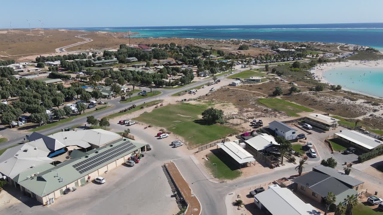 4k의 작은 녹색 마을 앞에서 해변 청록색 물 공중 촬영 슬로우 모션 60fps