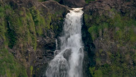 cascading waterfall splashing on rocky cliff in tropical rainforest