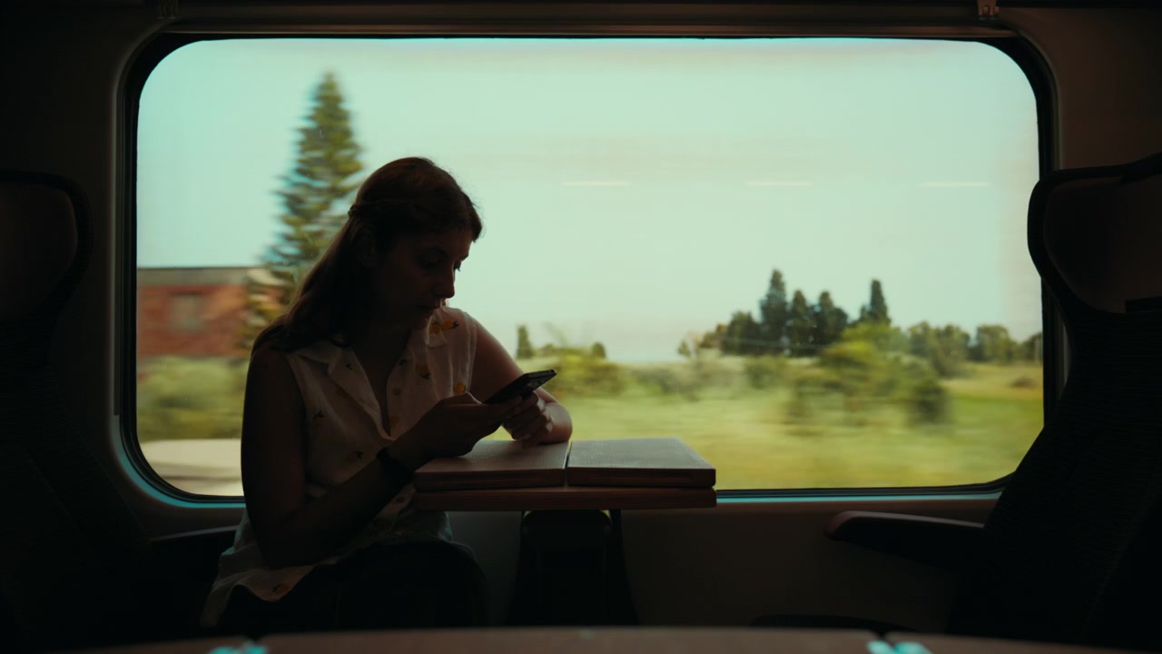 Silhouette di una donna che scrive messaggi al telefono mentre viaggia in treno