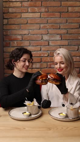 dos mujeres disfrutando de hamburguesas en un restaurante