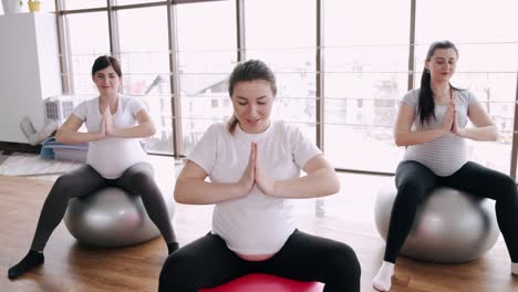 mujeres embarazadas están haciendo ejercicios prenatales en bolas de fitness en un gimnasio