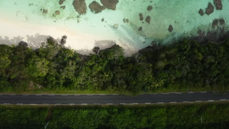 Toma-Aérea-De-Arriba-Hacia-Abajo-De-Una-Playa-Aislada-De-Arrecifes-De-Coral-Y-Una-Carretera-Desierta-En-Las-Islas-De-Lealtad