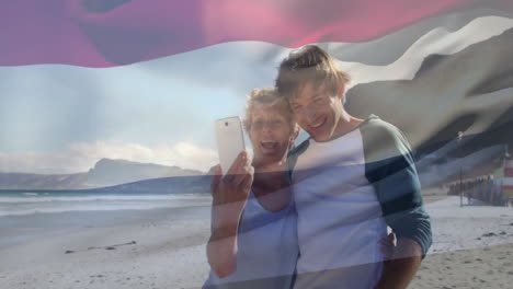Taking selfie on beach, couple with waving flag overlay in animation