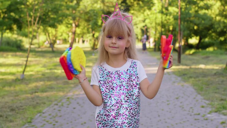 Bambina che tiene in mano un giocattolo sensoriale Pop It in silicone morbido e colorato, la bambina gioca a Pop It.