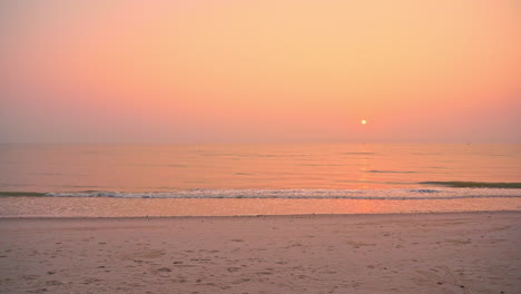 Farbenfroher-Ozeansonnenuntergang-Am-Strand-Mit-Dunstiger-Sonne-In-Der-Ferne