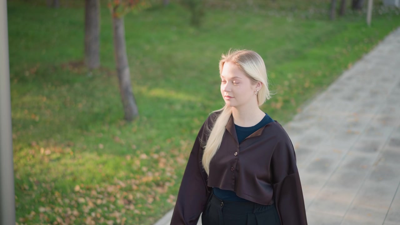 Young Blonde Woman Walking Along a Park Path