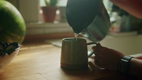 young woman pouring a cup of tea on her kitchen counter