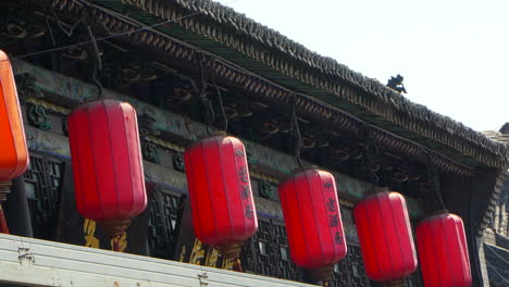 chinese red lanterns with inscriptions hung from a traditional house