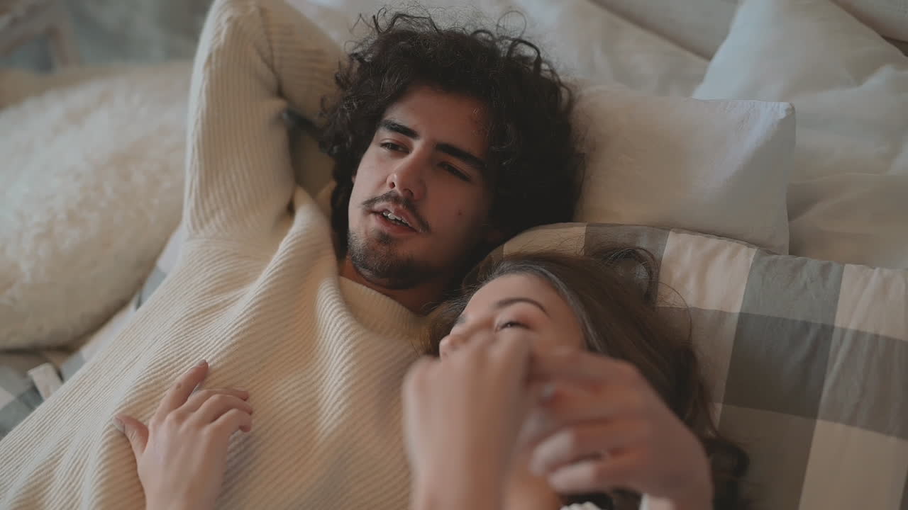 close up of young romantic cute couple lying in bed talking in love and  wearing winter clothes