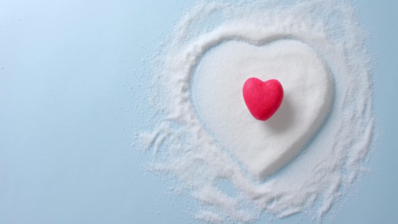 파란색 배경에  ⁇ 은 심장 모양의 설탕 위의 클로즈업, 복사 공간, 슬로우 모션