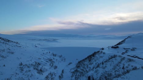 closing up drone footage of huge dam on the side of frozen mountain lake in southern norway