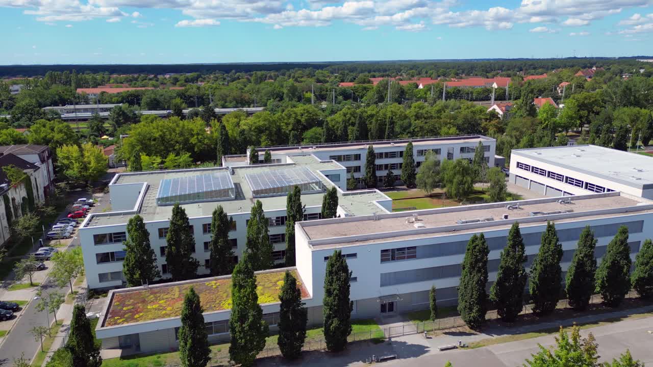 Hennigsdorf High School showcasing its modern architecture, sports facilities, parking area, surrounding urban landscape. Marvelous aerial view flight panorama overview drone