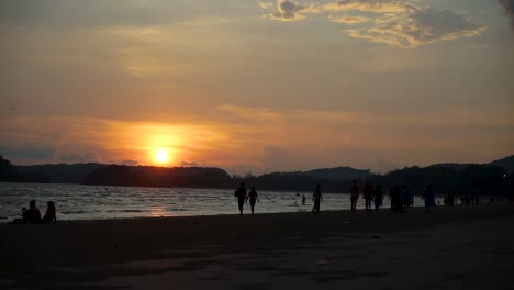 ao nang beach time lapse as the sun sets over the mountains in the background as tourists and locals cover the beach to watch the beautiful sunset in krabi thailand