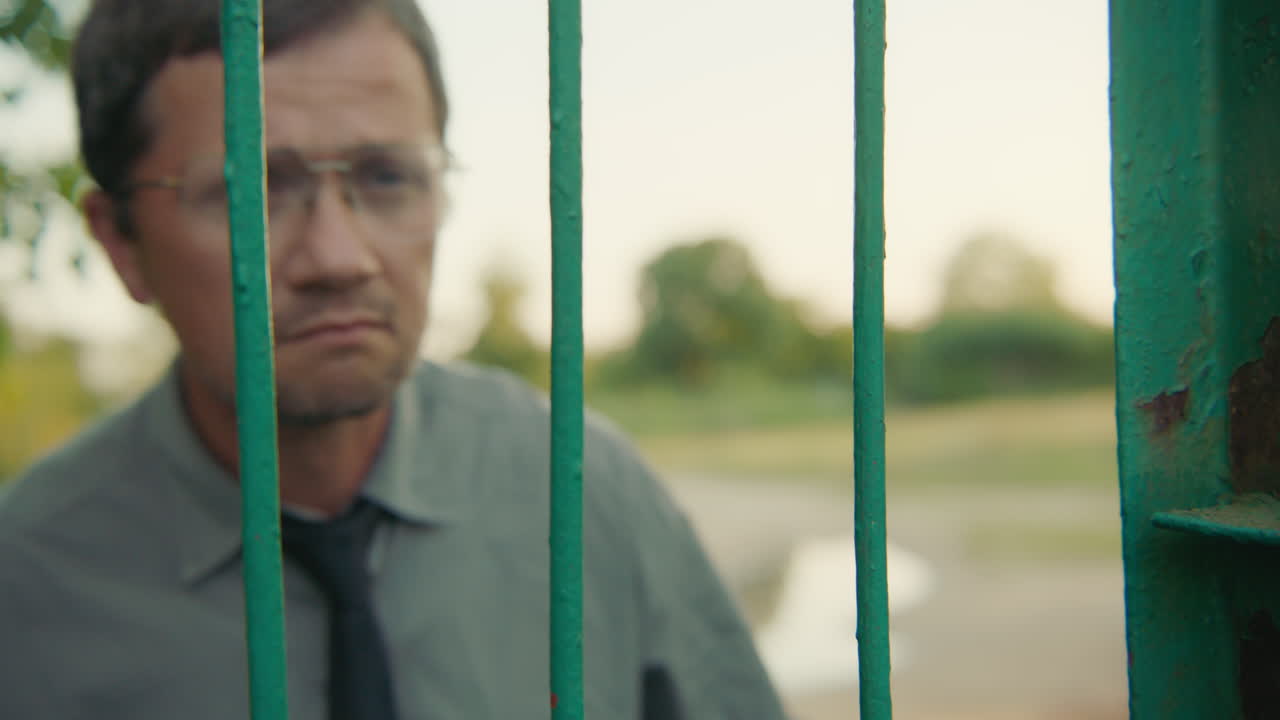 Man Looking Through a Fence