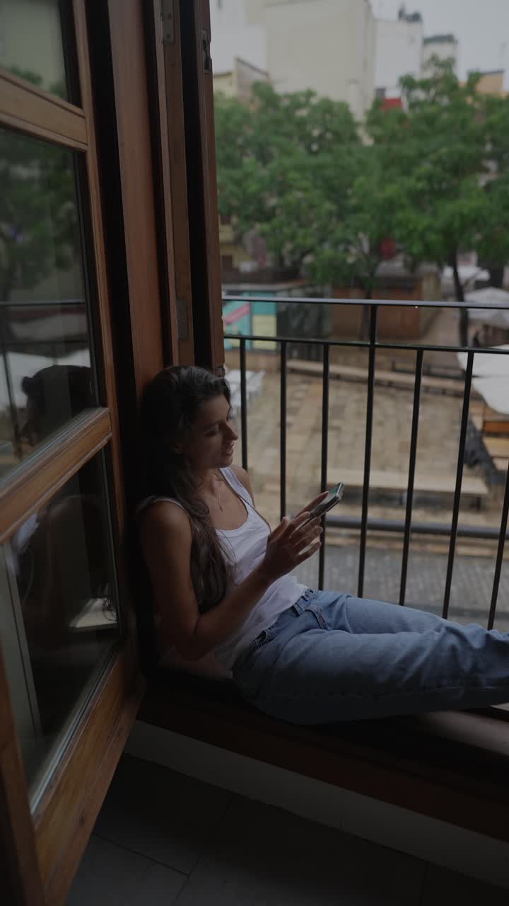 mujer sentada en el balcón bajo la lluvia