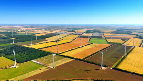 colorful fields with multiple wind turbines. vast nature landscape used for green energy production. aerial perspective