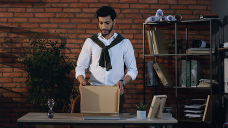 Stylish-Arabian-Businessman-Packing-A-Box-With-Office-Stuff-From-His-Table-And-Leaving-The-Office-With-This-Box-In-Hands-As-Been-Fired