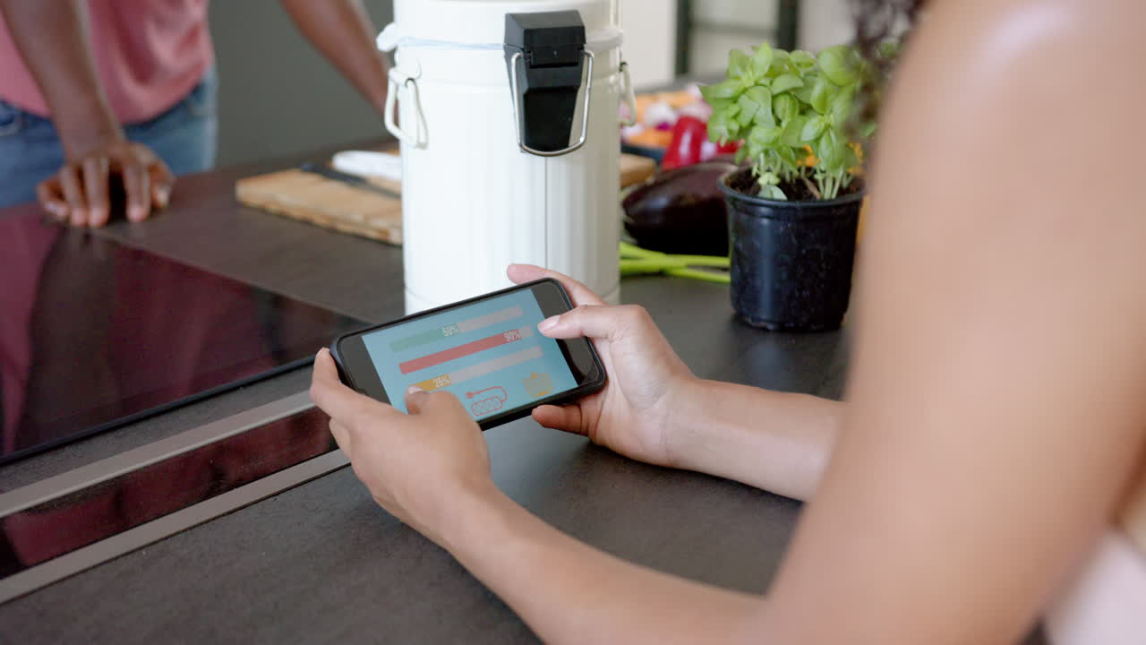 Holding smartphone, person checking health app while sitting at kitchen counter