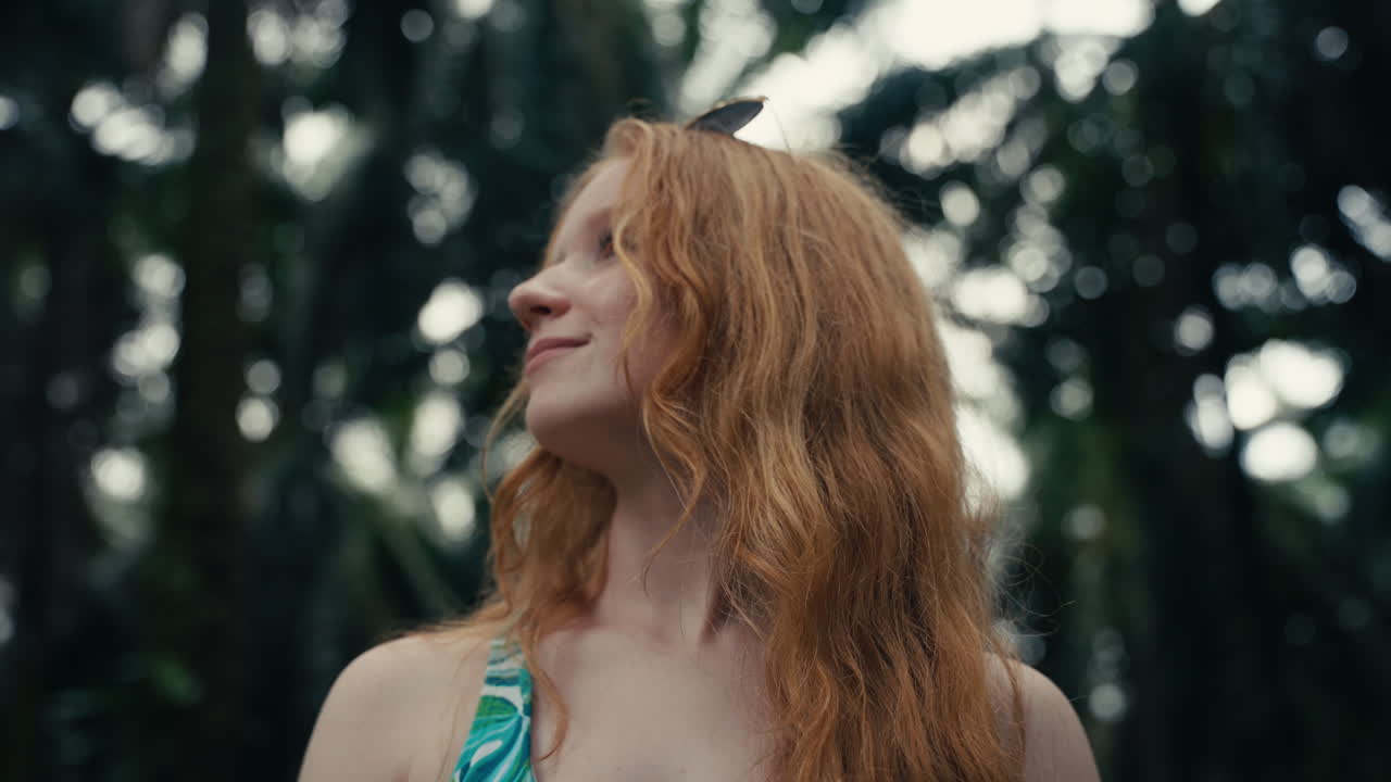 Portrait of a red-haired woman looking up in nature