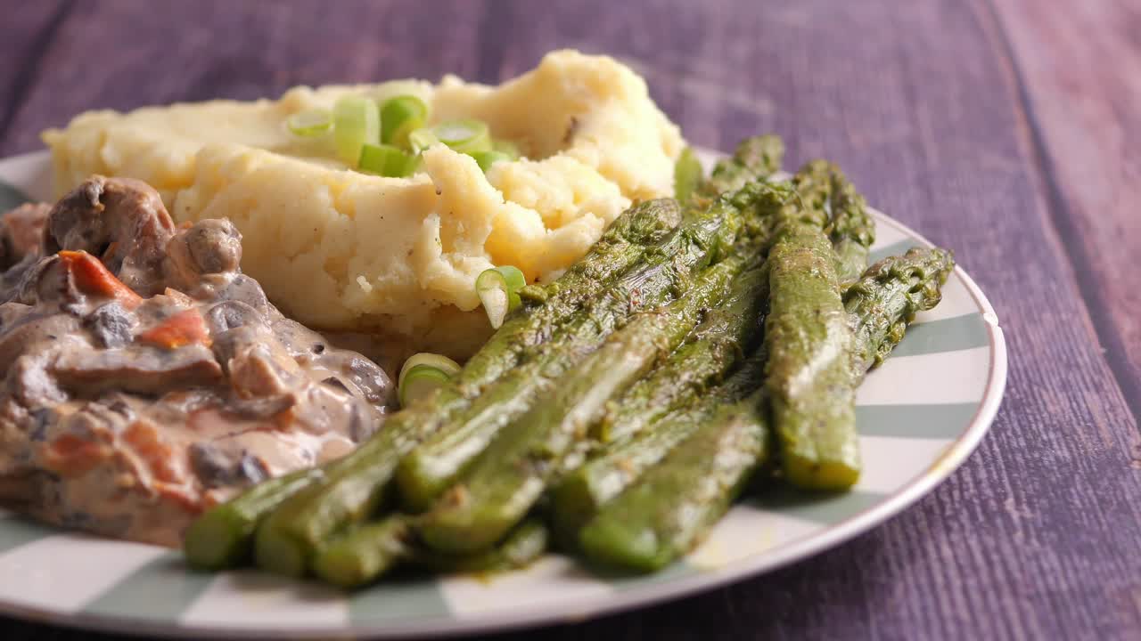 Plate of Mashed Potatoes, Asparagus, and Creamy Mushrooms on a Wooden Table