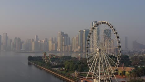 4k:-Luftaufnahme-Des-Khalid-sees-Von-Sharjah-Mit-Der-Skyline-Der-Stadt-Und-Dem-Auge-Der-Emirate-An-Einem-Frühen-Morgen-In-Den-Vereinigten-Arabischen-Emiraten