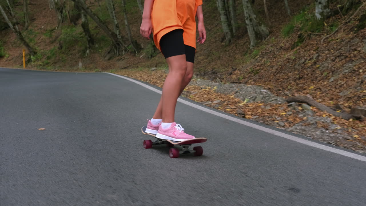 una mujer joven patinando en un camino de montaña.
