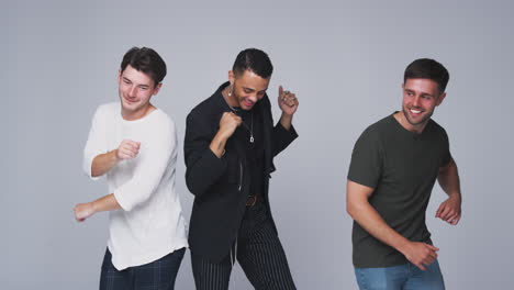 group studio portrait of multi-cultural male friends dancing in slow motion together