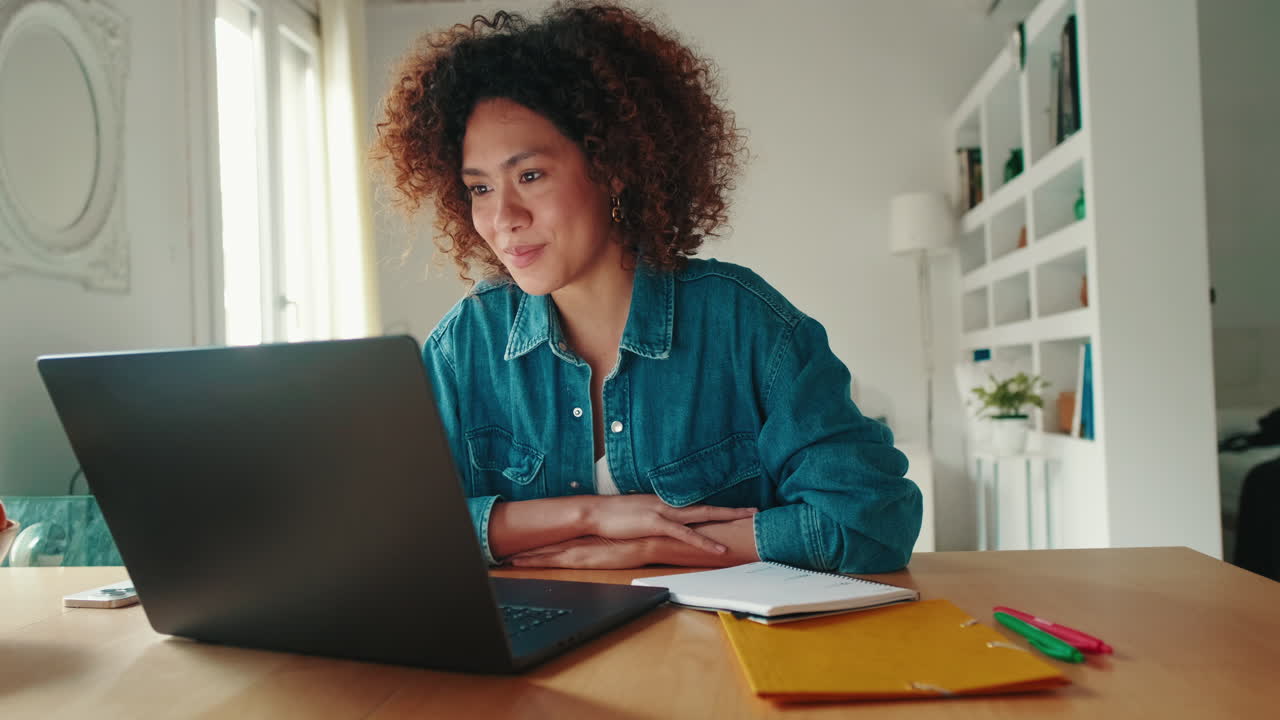 Young Woman Working on Laptop and Taking Notes in Home Office