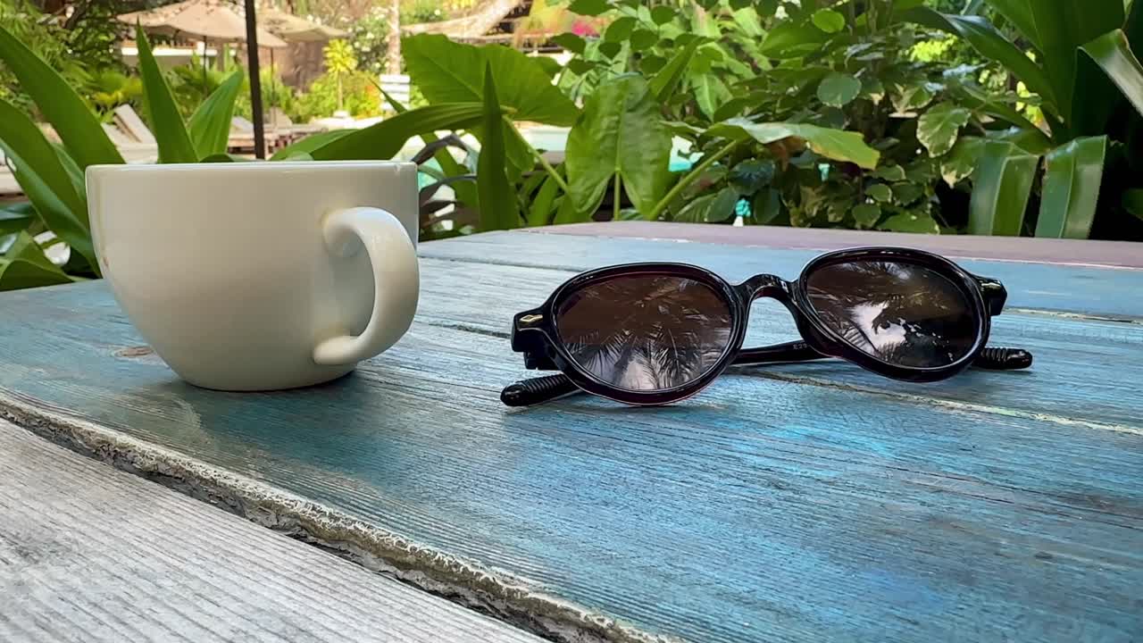 Close Up of Sunglasses and Coffee Cup on Wooden Bench in Tropical Resort Morning Paje Zanzibar Tanzania