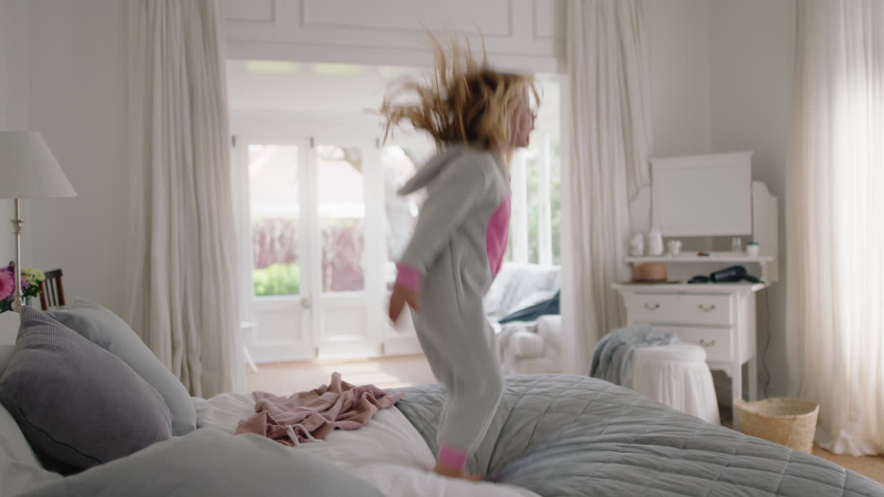 niña feliz bailando en la cama divirtiéndose niño de humor lúdico disfrutando de la mañana de fin de semana en casa