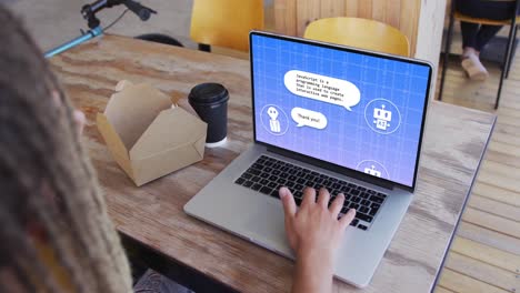 Biracial-businessman-with-dreadlocks-eating-lunch-using-laptop-for-ai-digital-chat-in-office