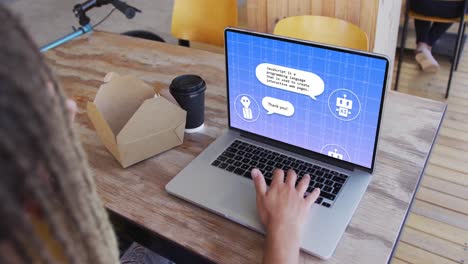 un hombre de negocios biracial con dreadlocks almorzando usando una computadora portátil para un chat digital en la oficina.