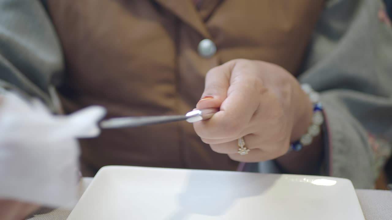 Close-up of a person's hands wiping cutlery with a tissue