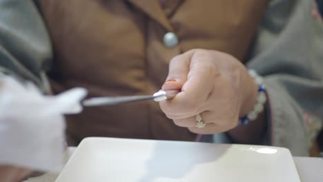 close-up of a person's hands wiping cutlery with a tissue
