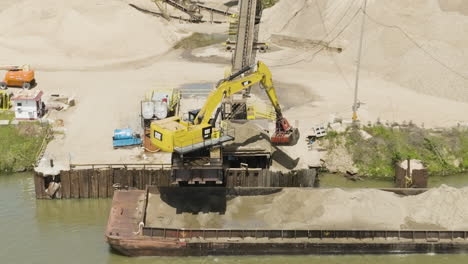 excavator with clamshell bucket unloading sand from the barge