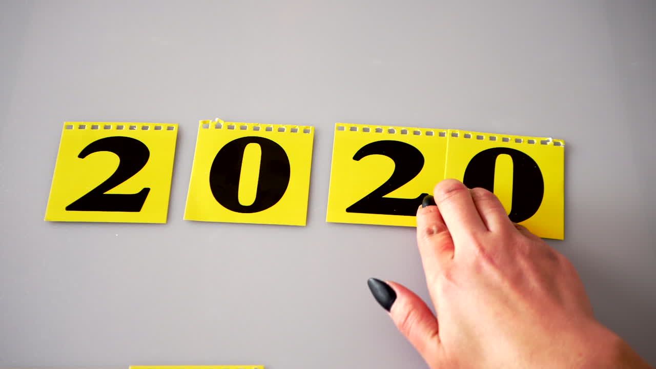 Mano che gira un calendario giallo a fogli mobili per il nuovo anno.