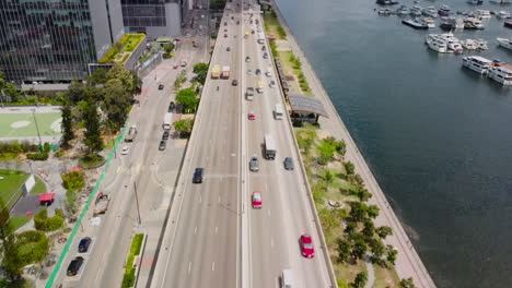 drone ariel dolly push in tilting up revealing kwun tong highway traffic boat pier. 4k hd footage showing sunny day ngau tau kok traffic.